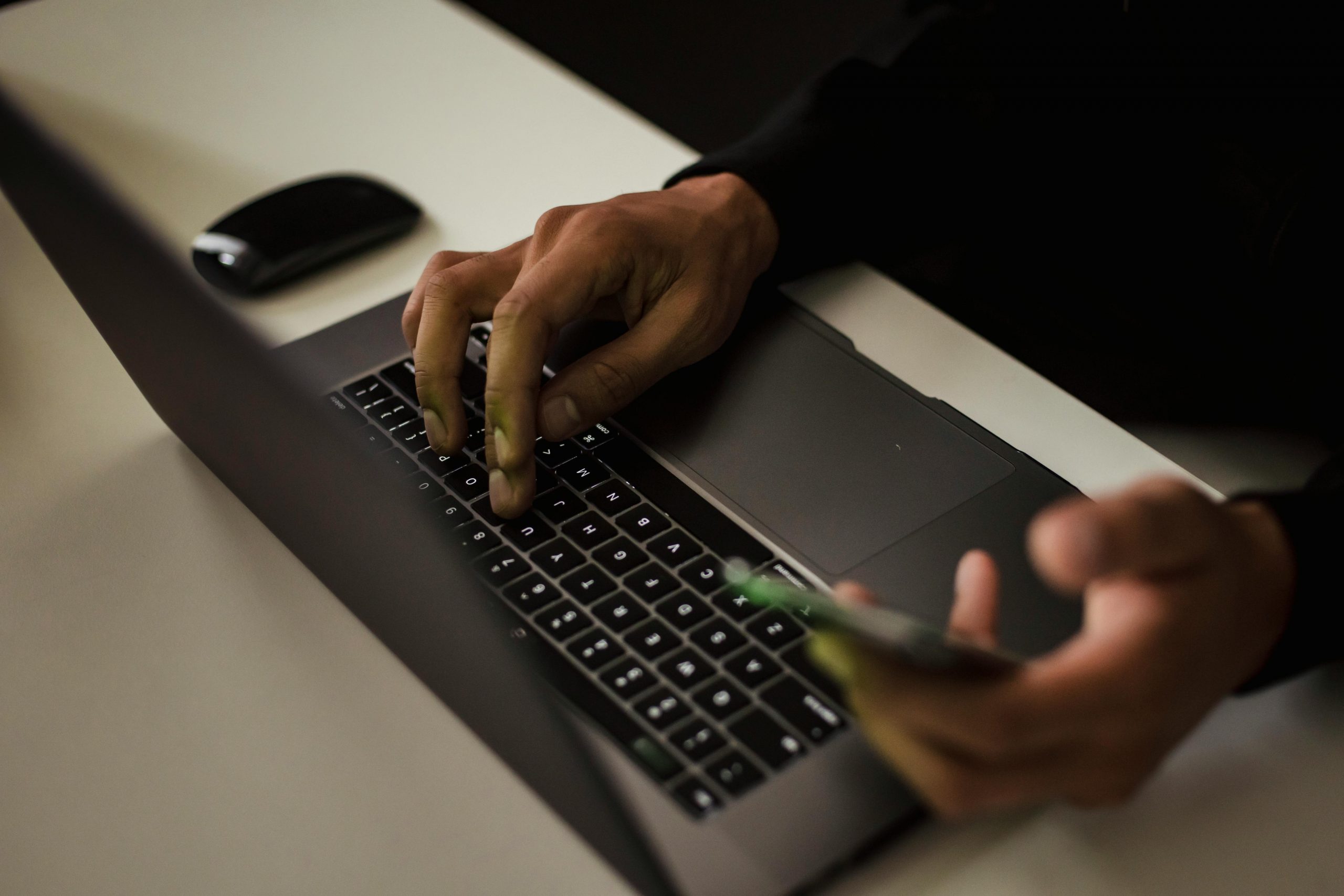 Crop Gesichtslosen Mann, Der Auf Laptop Und Mit Smartphone Tippt